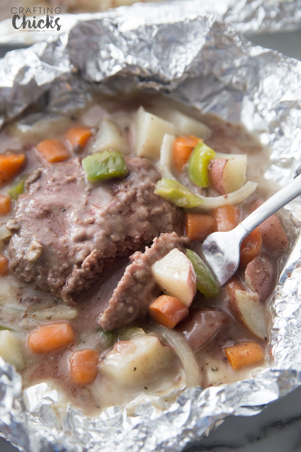 Tin foil dinner cooked with hamburger, carrots, celery, potatoes, and onions in a sauce.
