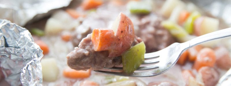 Tin foil dinner cooked with hamburger, carrots, celery, potatoes, and onions in a sauce.