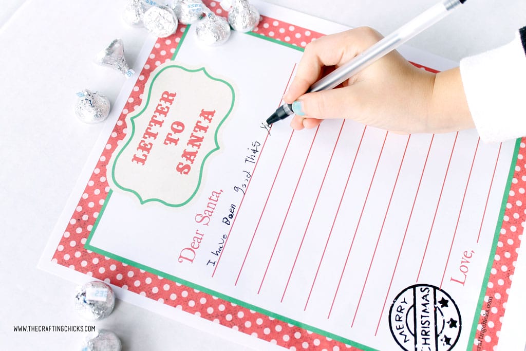 Child writing on Free Printable Letters to Santa with pens and Hershey Kisses.