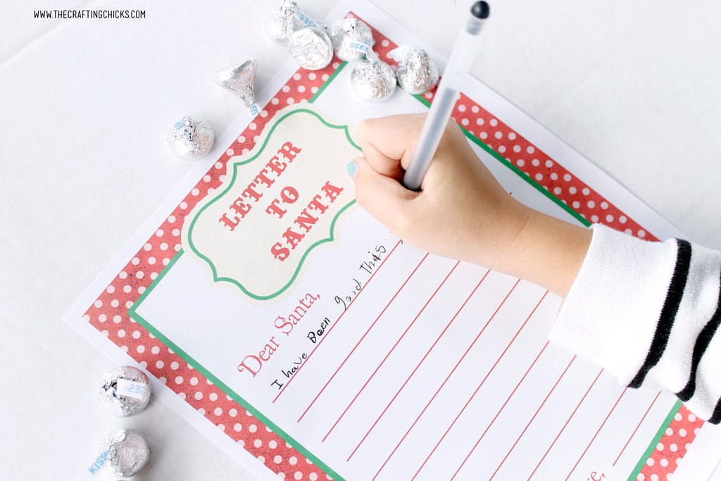 Child writing on Free Printable Letters to Santa with pens and Hershey Kisses.