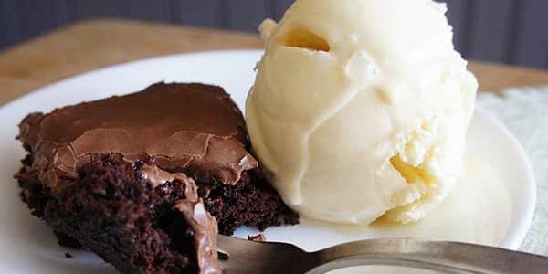 zucchini brownie with chocolate frosting and a scoop of vanilla ice cream