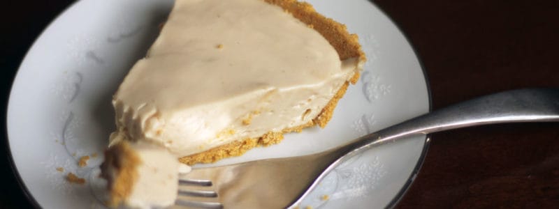 Cheesecake with graham cracker crust on a plate with a fork