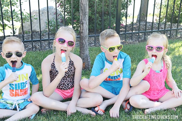 4 kids sitting in the shade eating popsicles 