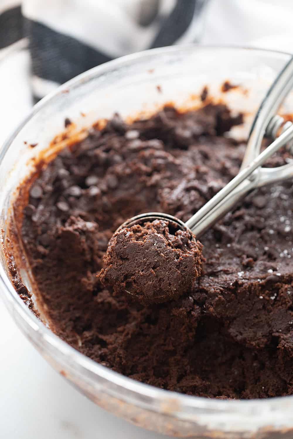 A cookie scoop has Decadent Double Chocolate Crinkle Cookie batter in it ready to place on pan for baking