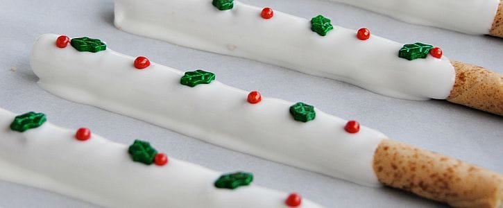 Holly Jolly Cookie Sticks are the perfect no bake treat for family, friends and neighbors! Vanilla filled cookie sticks are dipped in white chocolate and decorated with festive holly sprinkles!