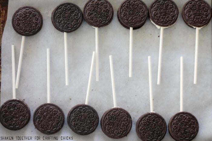 Oreo pops waiting to take a dunk in melted chocolate and sprinkles for Ball Drop Oreo Pops!