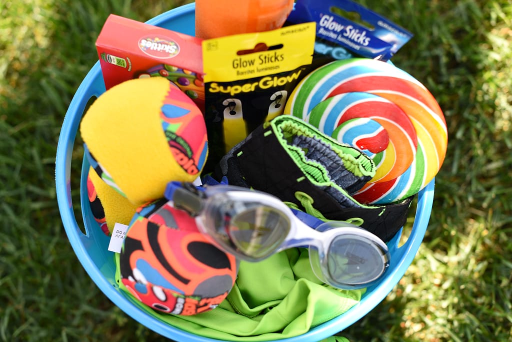 Blue sand bucket full of water toys, goggles, glow sticks and candy to make a summer gift.