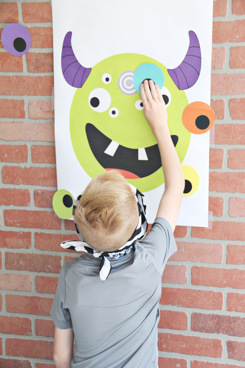 Little boy playing Pin the Eye on the Monster Halloween Game
