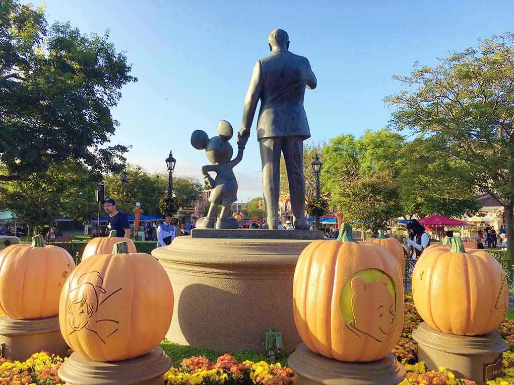 Statue of Walt Disney and Mickey Mouse in Disneyland with Pumpkins surrounding.