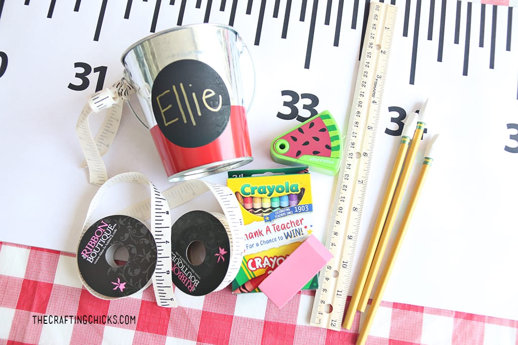 small tins with children's names on them with crayons, rulers, and pencils for a back to school gift idea