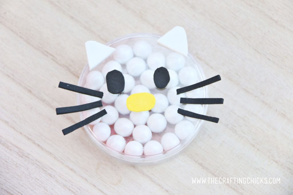 White foam ears added to a clear round favor container filled with white Sixlets to make a Hello Kitty Face