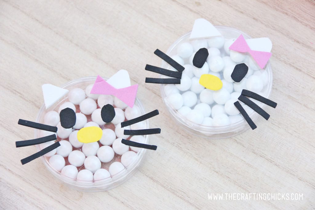 Small clear candy dishes filled with white round candies and decorated to look like Hello Kitty with foam stickers