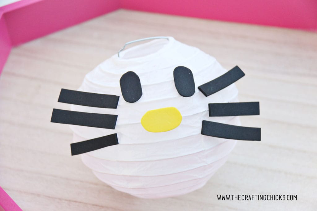 Black foam oval eyes White mini paper lantern with cut out foam shapes to make Hello Kitty DIY Paper Lanterns