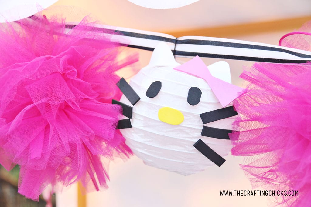 Hot Pink Tulle Pom-Pom and Hello Kitty DIY Paper Lanterns strung together on a black and white striped satin ribbon to make a garland