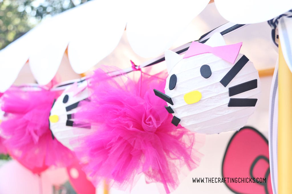 Hot Pink Tulle Pom-Pom and Hello Kitty DIY Paper Lanterns strung together on a black and white striped satin ribbon to make a garland