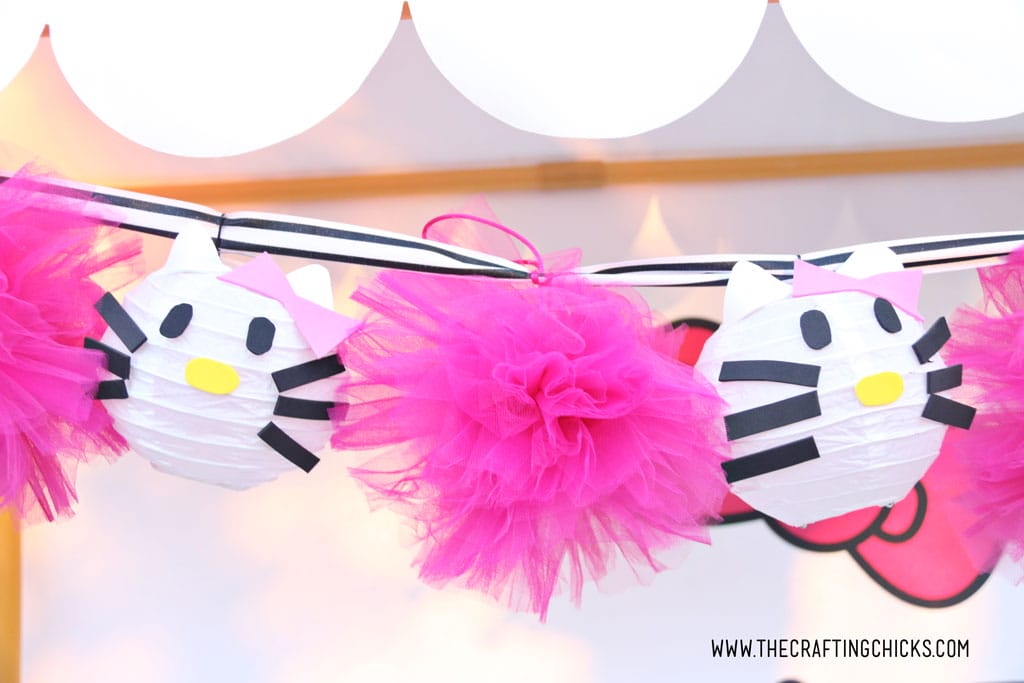 Hello Kitty Paper Lanterns strung up on a garland with bright pink pom poms