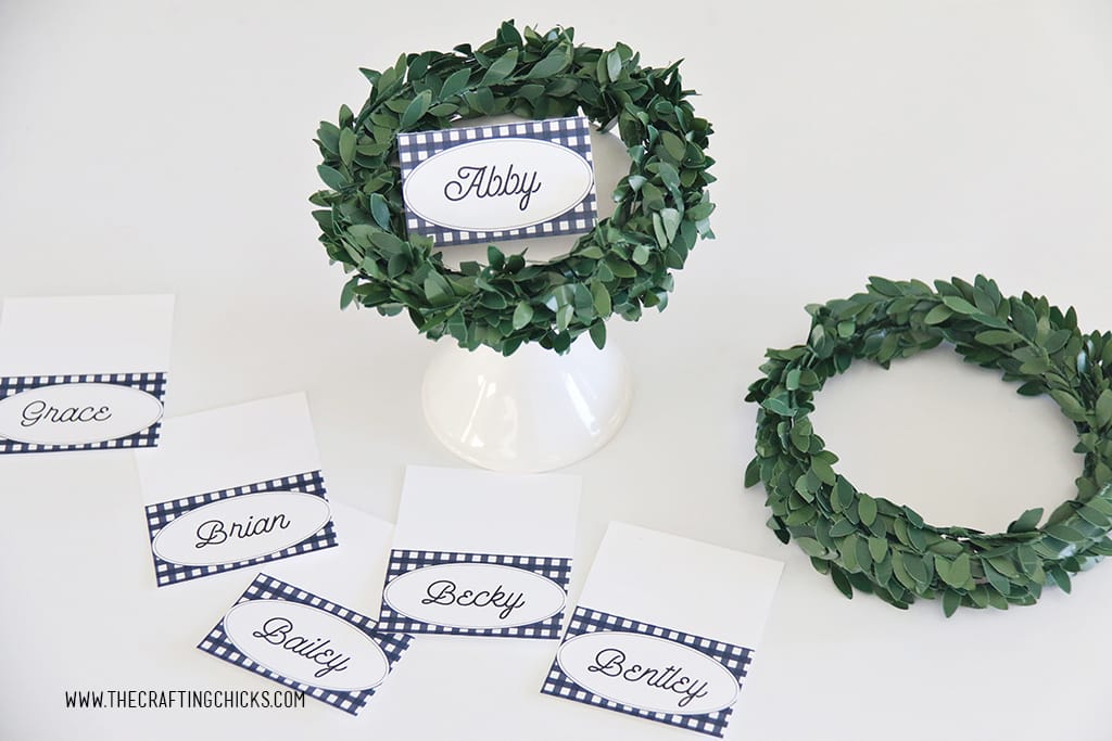 Thanksgiving navy and white check printable place cards on a white stand with a wreath on them.