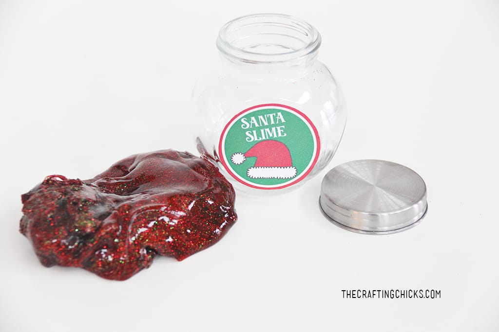 Read slime with red and green glitter. Small clear glass jar and lid on the side for Santa Slime