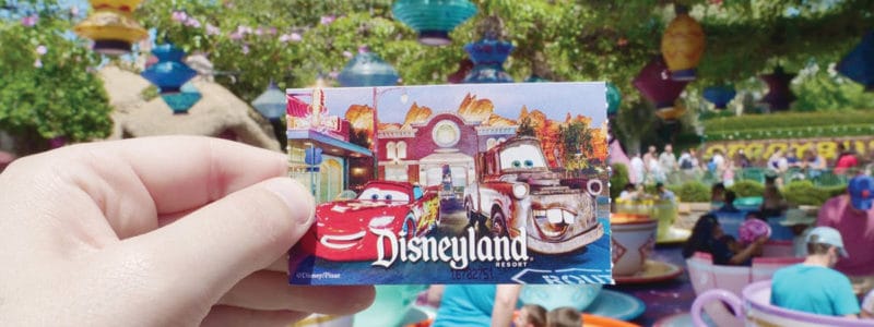 Disneyland ticket in front of teacup ride.