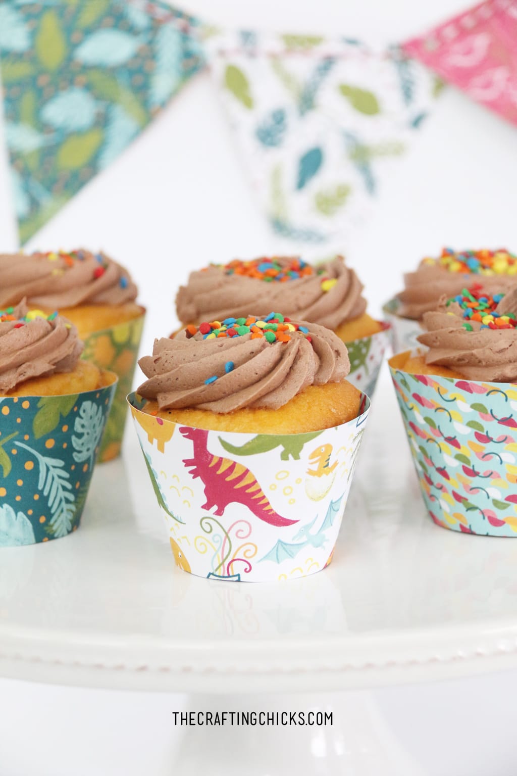 Cupcakes with chocolate frosting and DIY dinosaur cupcake paper wrappers.