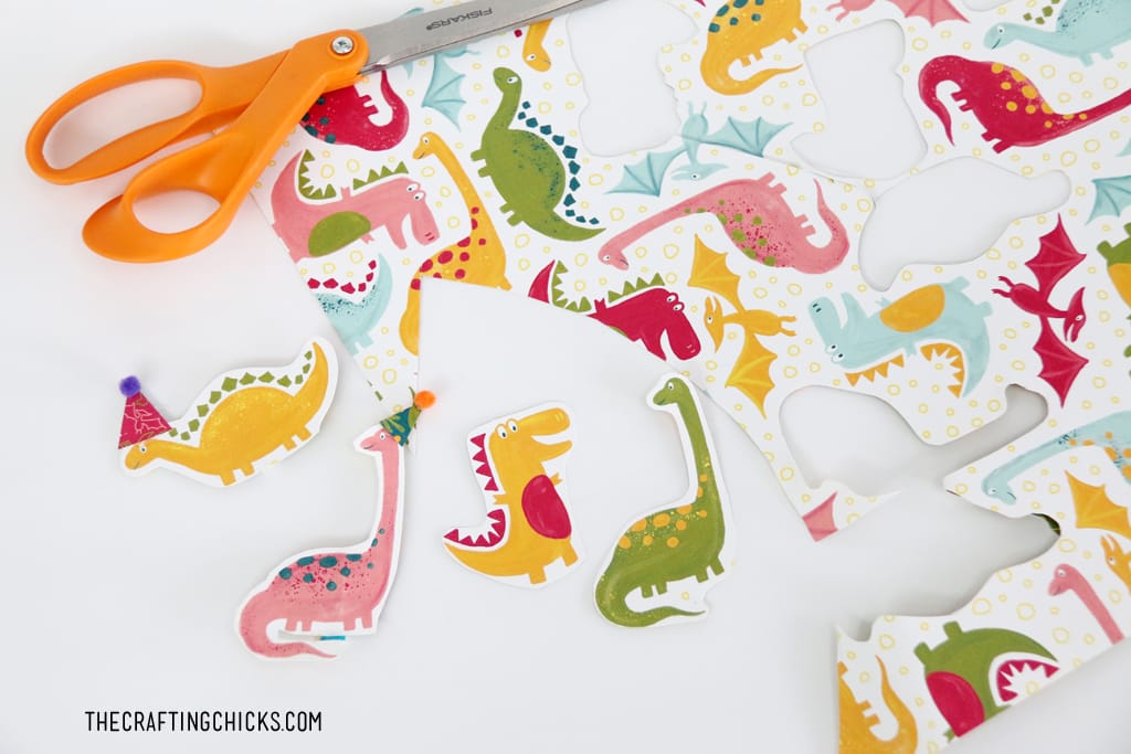 Dinosaurs cut out from scrapbook paper to make Cute Dinosaur Cupcake toppers.
