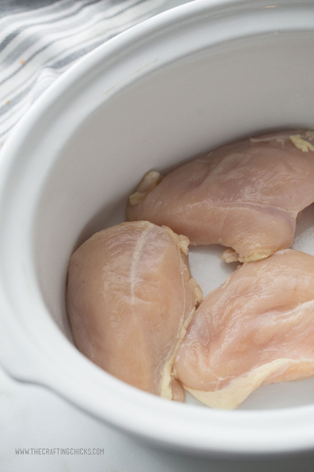 Raw Chicken breasts in a crockpot ready to be cooked.
