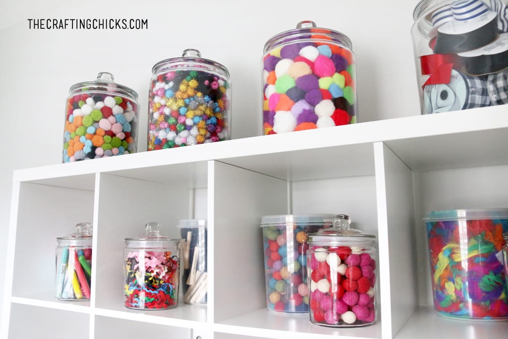 Apothecary jars filled with colorful pompoms and other crafting supplies for a craft room design