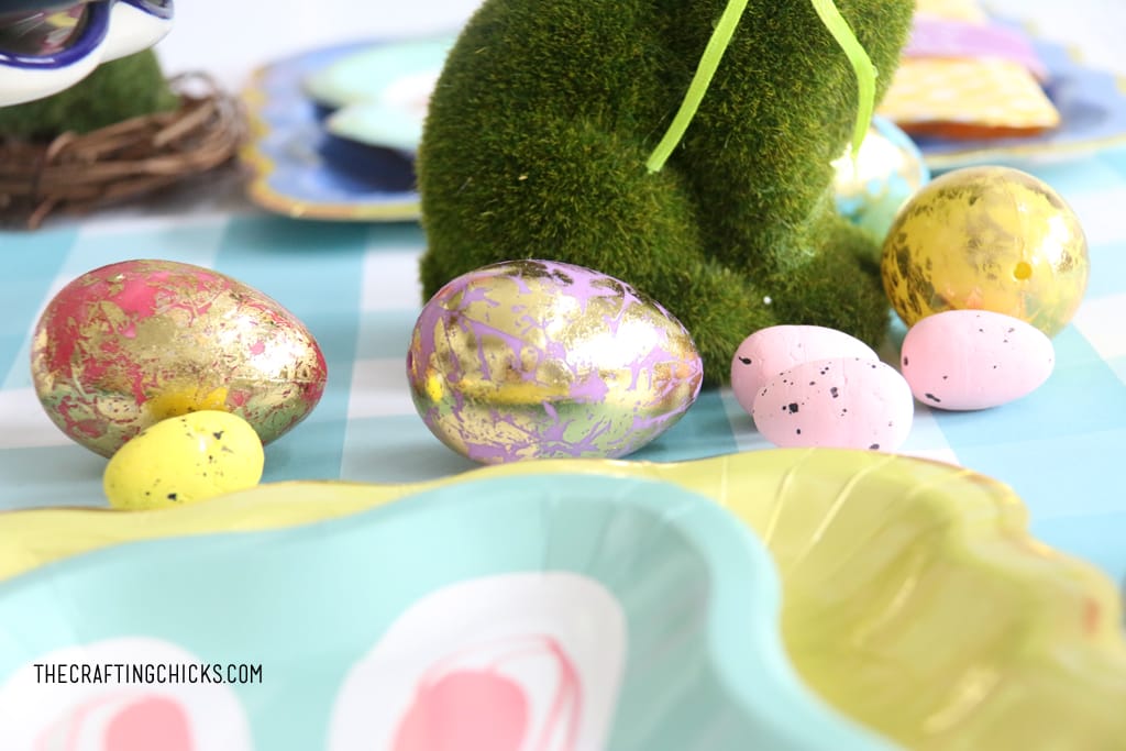 Gold foil eggs and small speckled eggs on an Easter table as decoration.