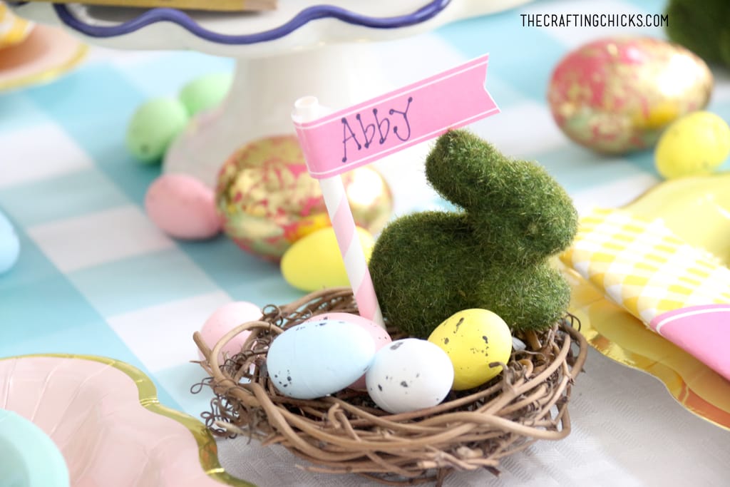Easter table for kids with faux grass bunny decoration and faux eggs as in a nest with a name tag as table decoration.