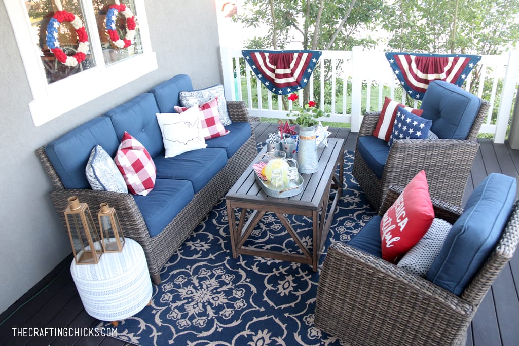Backyard deck with dark wicker furniture and pops of red, white and blue patriotic decor.