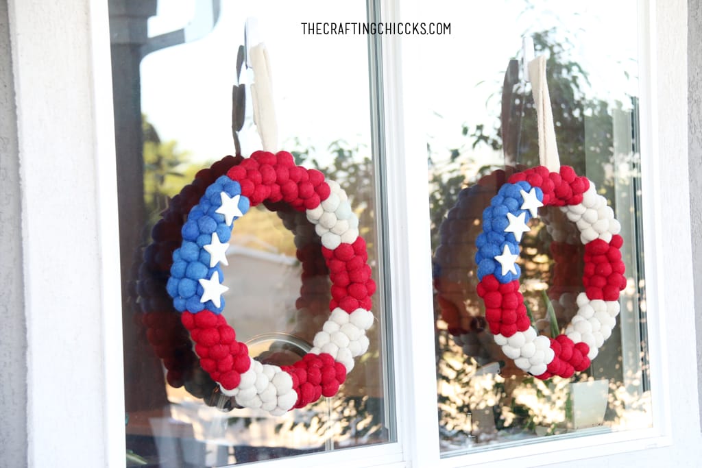 Patriotic Pom Pom wreaths hung on a window for deck decorations