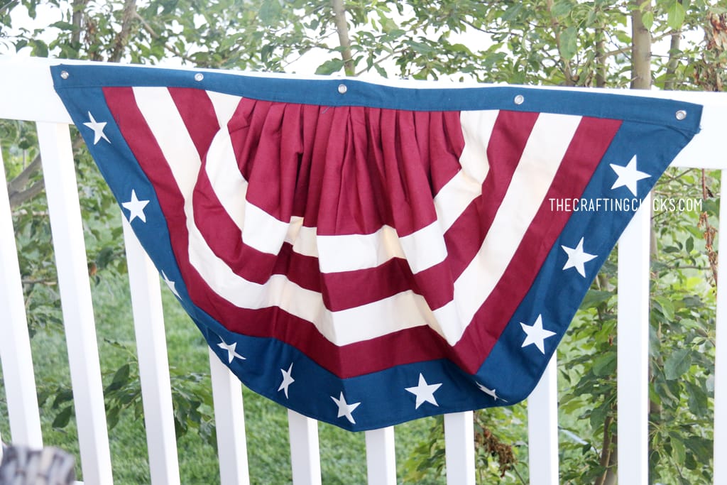 Red, white, and blue patriotic bunting on a white fence railing.