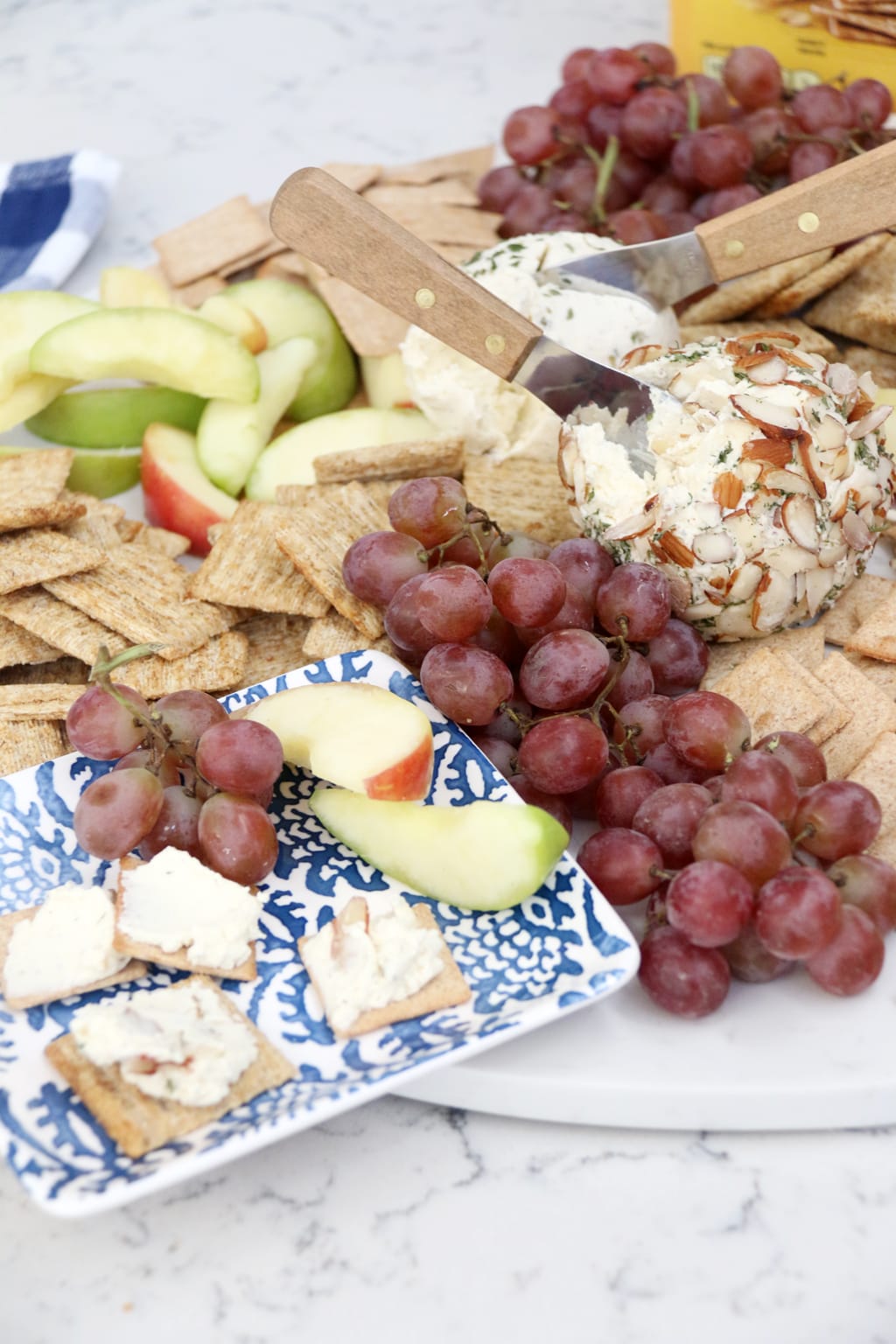 Simple Ranch Cheese Ball on crackers with grapes and apple slices.