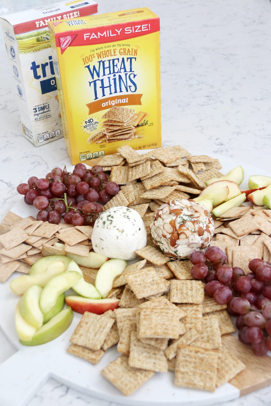 Simple Ranch Cheese Ball with crackers, apple slices, and grapes on a board.