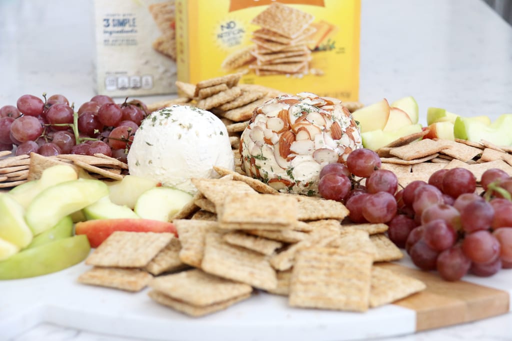 Simple Ranch Cheese Ball with crackers, apple slices, and grapes on a board.