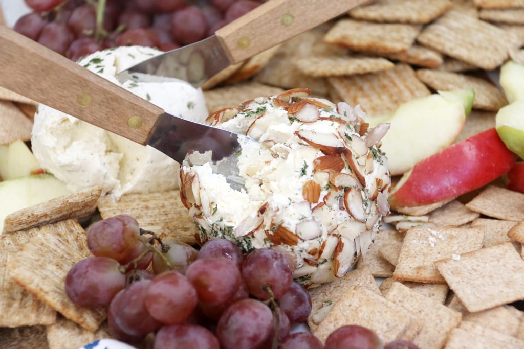 Ranch Cheese ball covered in slivered almonds on a plate with crackers.