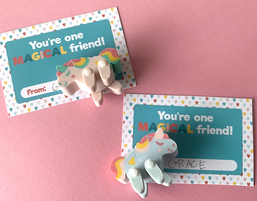 Pink and green unicorn movable erasers on free printable valentines staged on a pink background