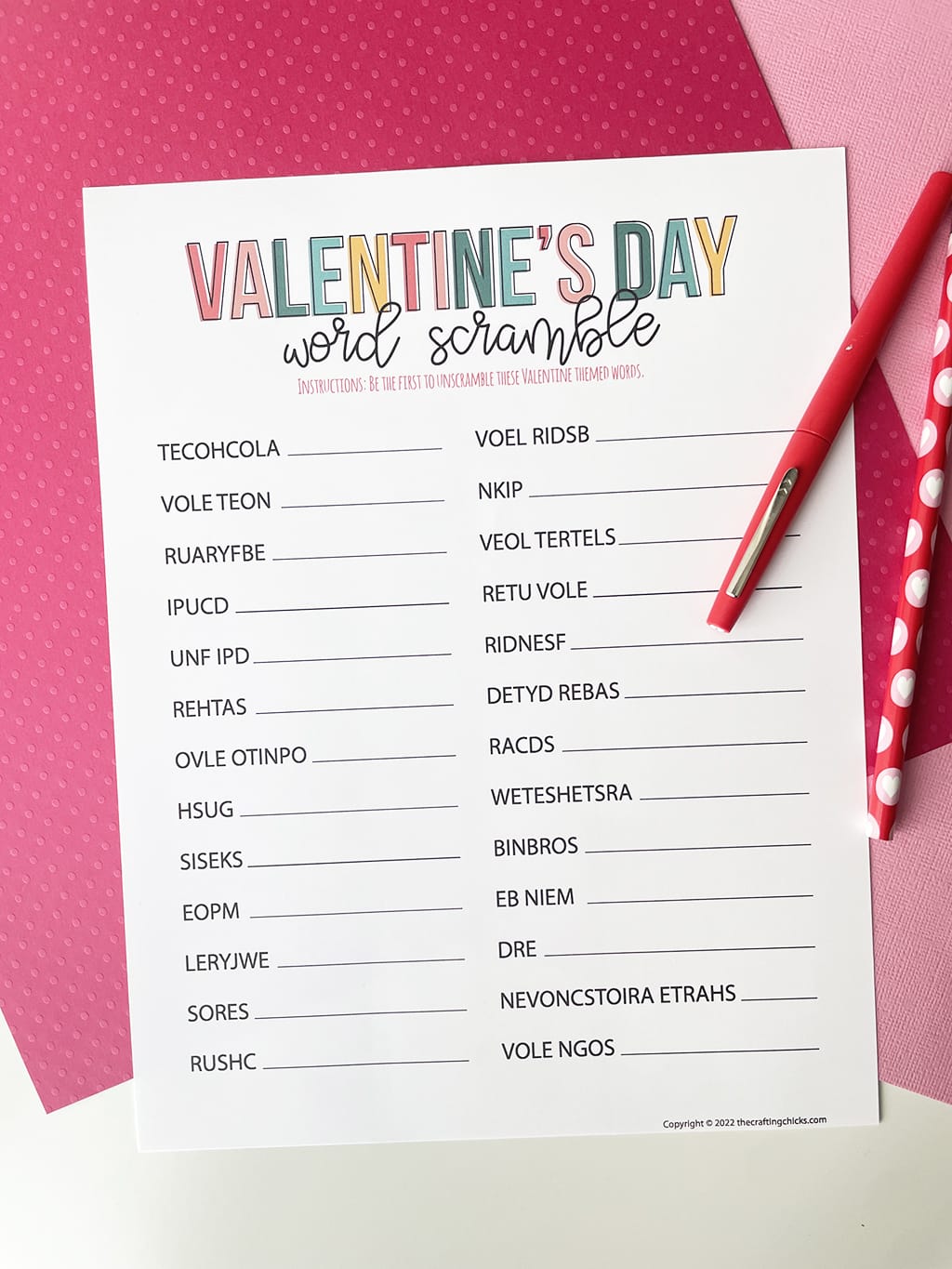 Valentines Day Word Scramble Printable Game printed out and placed on a dark pink and light pink paper backdrop. With a red fineline marker and a Valentine pencil.
